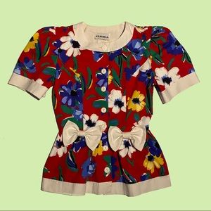 Woman’s short puffy sleeve floral pattern button down shirt w/ flared pleats.